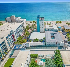 Un hotel con varias edificaciones, zona de piscina y vista al mar.