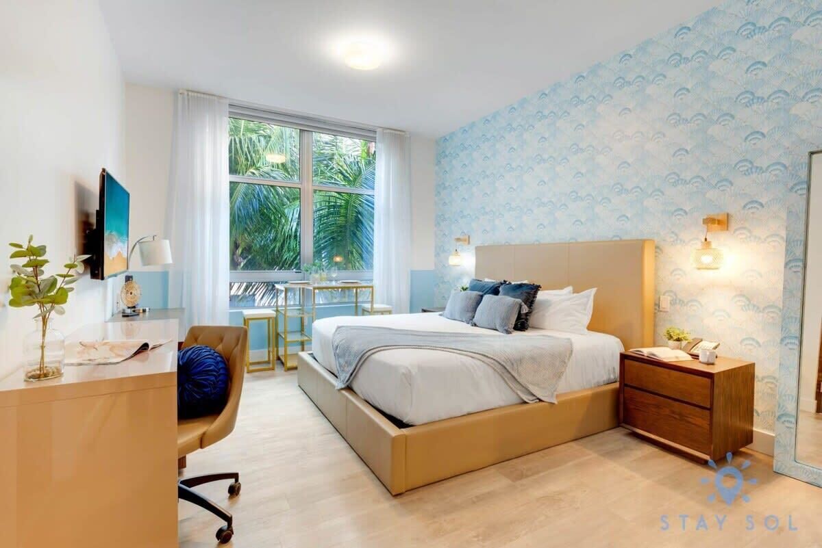 A modern bedroom with a bed, bedside tables, a desk, and a chair.