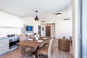 A modern kitchen with a dining area, featuring a large table, chairs, and a TV mounted on the wall. - Rooftop Pool + Hot Tub|Hollywood Beach|Near Beach (Hollywood)