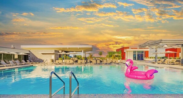 A swimming pool with lounge chairs, a pink flamingo float, and a gas station in the background. - Rooftop Pool + Hot Tub|Hollywood Beach|Near Beach (Hollywood)