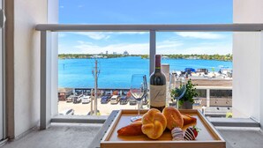 Un balcón con vistas al mar, una botella de vino y una bandeja con pan y una copa.