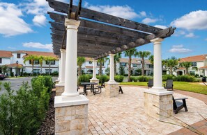 A covered patio area with stone pillars, picnic tables, and outdoor seating.