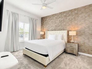 A modern bedroom with a large bed, a ceiling fan, and a textured wall.