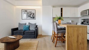 A modern living room with a dark grey sofa, a wooden coffee table, and a dining area with a wooden table and chairs. - w* | Modern 1BR in New Building in Roma Norte (Ciudad de México)