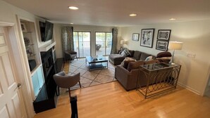 A spacious living area with a sofa set, a coffee table, and a glass-top table. There is a sliding glass door leading to a balcony. - Beautiful 4 Bedroom River Front House in Downtown (Augusta)