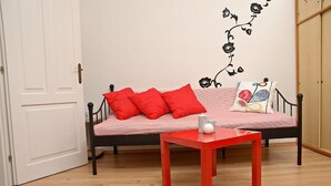 Een kamer met een bed, een rode tafel en een decoratie aan de muur.