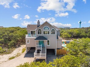 A two-story house with a balcony, a garage, and a view of the surrounding landscape.