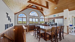 A spacious kitchen with a large island, wooden ceiling beams, and large windows. - OCEANSIDE:  Private Pool, beautiful home on full acre lot! (Corolla)