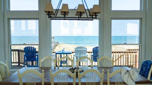 Ein Essbereich mit Blick auf den Strand und den Ozean durch große Fenster.