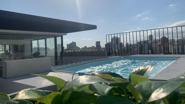 A rooftop pool with a city view, surrounded by greenery and a modern building structure. - Big apt Downtown Santo Domingo - 202 (Santo Domingo)
