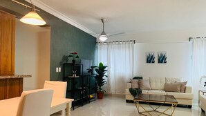 A modern living room with a white sofa, a glass coffee table, and a dining area with a white table and chairs. - Big apt Downtown Santo Domingo - 202 (Santo Domingo)