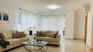 A modern living room with two beige sofas, a glass coffee table, and a potted orchid. - Big apt Downtown Santo Domingo - 202 (Santo Domingo)