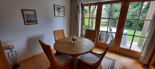 Un comedor con una mesa redonda de madera, sillas de mimbre y un ventanal con vistas al exterior.