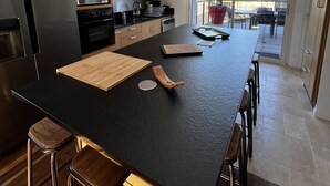 Una cocina moderna con una isla grande, electrodomésticos de acero inoxidable y una puerta corrediza de vidrio a un balcón.