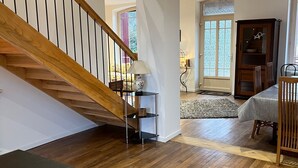 Un amplio salón con una escalera de madera, una mesa de comedor y un mueble empotrado.