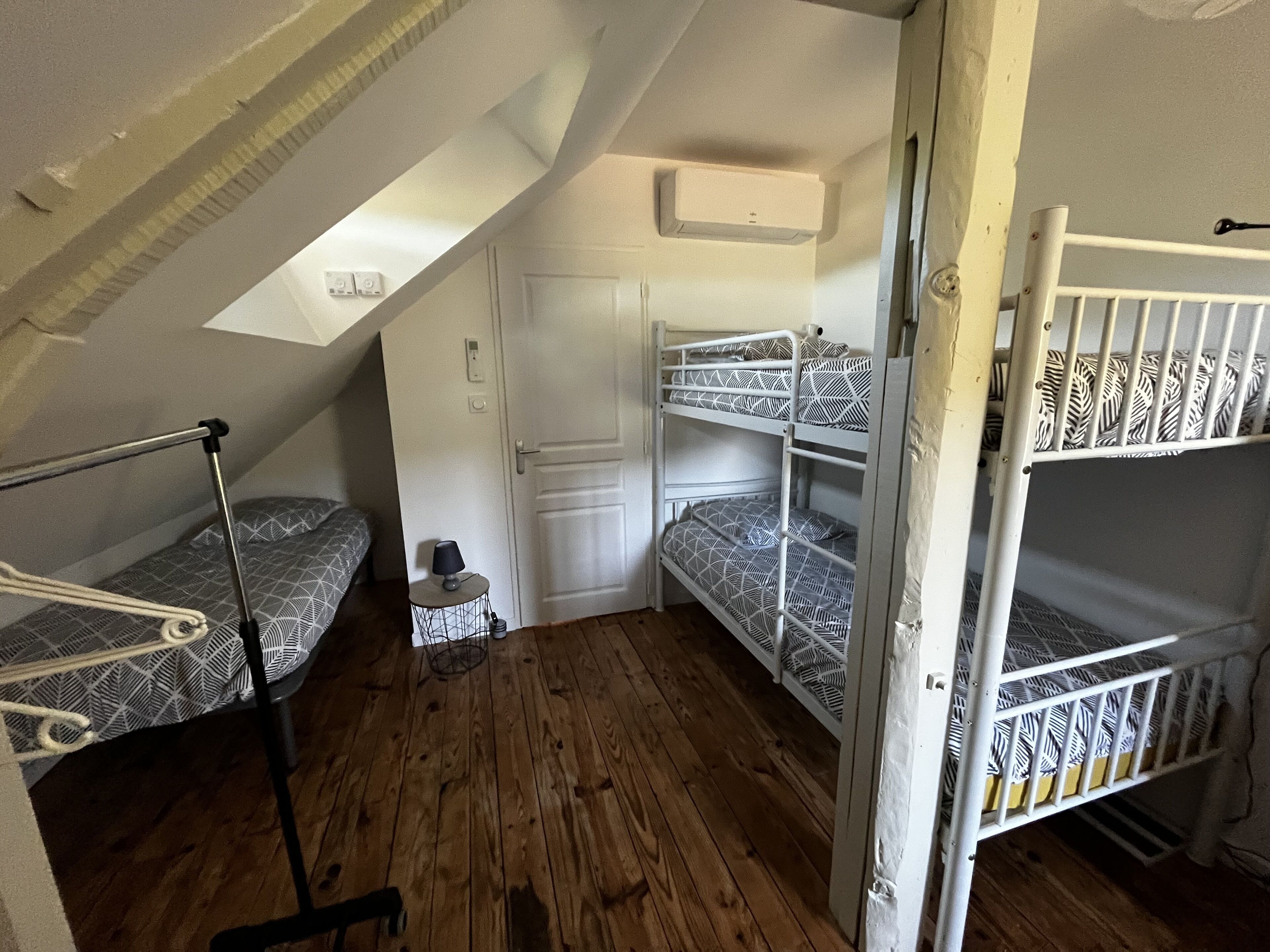 A compact room with bunk beds, a small table with a lamp, and a door.