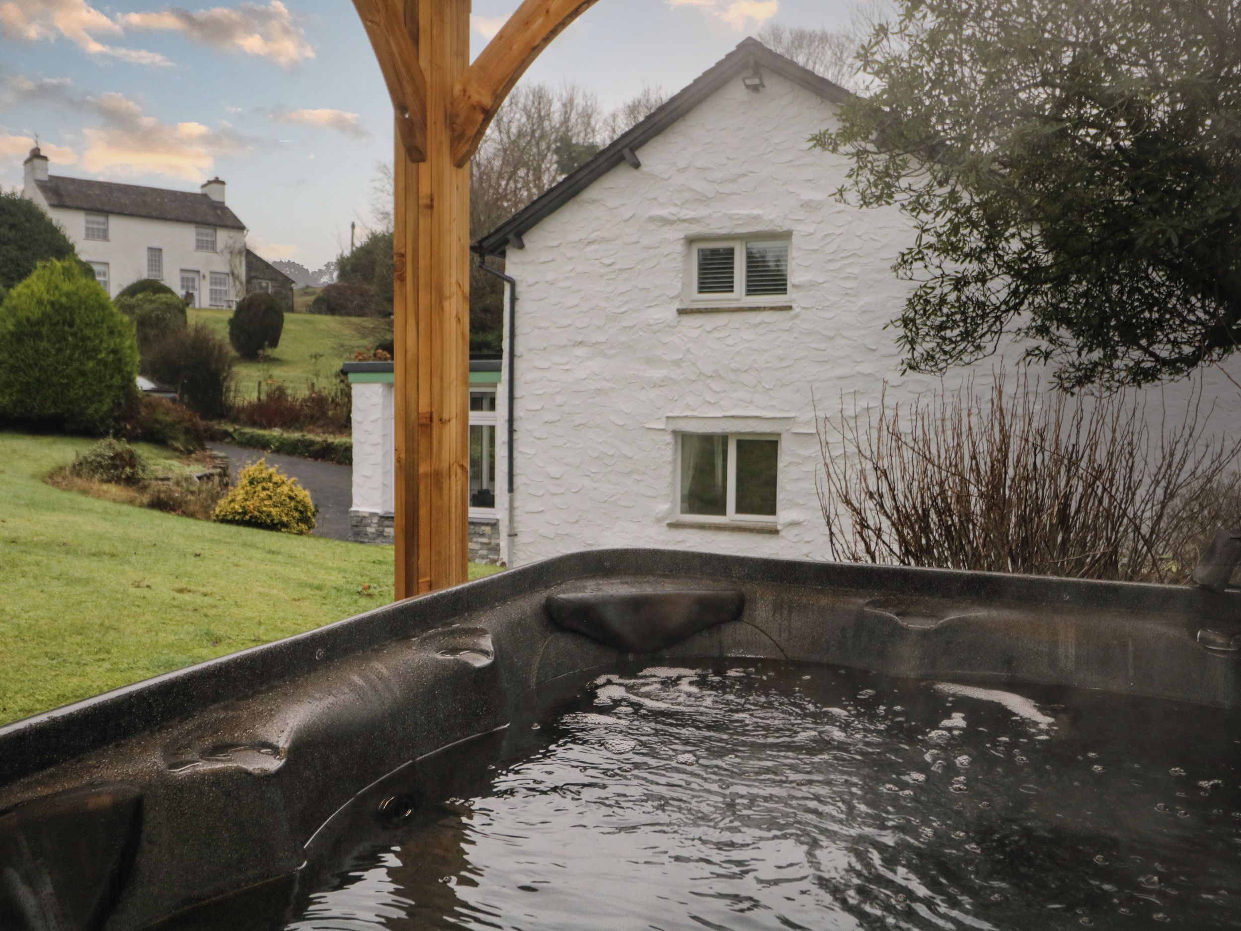 Un jacuzzi dans un jardin, avec une maison blanche en arrière-plan.