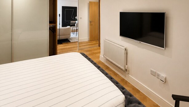 Un dormitorio con cama, televisor, armario y puerta corredera que da a un baño.