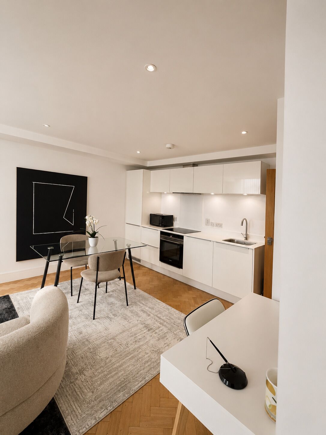 A modern kitchen with white cabinets, a black microwave, and a stainless steel sink.