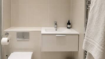 Un baño moderno con inodoro, lavabo y zona de ducha.