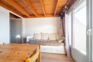 Relax in a spacious room with a high ceiling, featuring a comfortable seating area and a dining table.