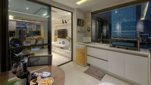 A modern kitchen with a dining area, a view of the living room, and a built-in grill. - Waiwai Cumbuco pé na areia por Carpediem (Caucaia)