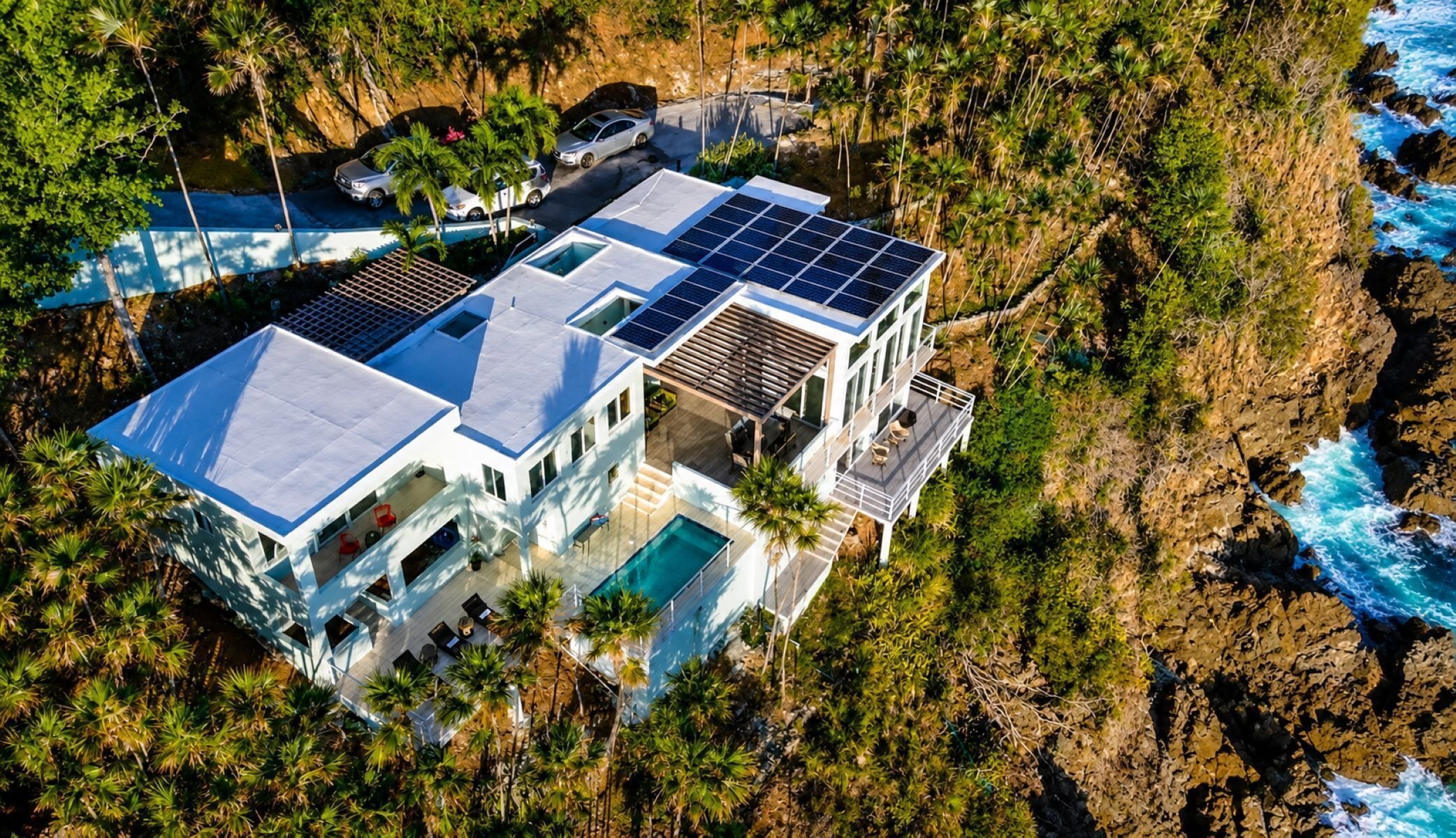 Une maison moderne dotée d’une piscine, de panneaux solaires et offrant une vue sur l’océan.