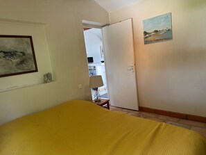A bedroom with a bed, a painting, and a door leading to another room. - SUPERB FIRST-FLOOR APARTMENT (Saintes-Maries-de-la-Mer)