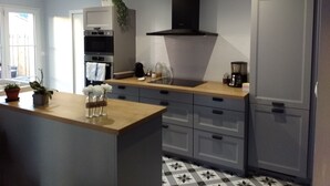 Een moderne keuken met grijze kastjes, een zwarte afzuigkap en een houten aanrecht.