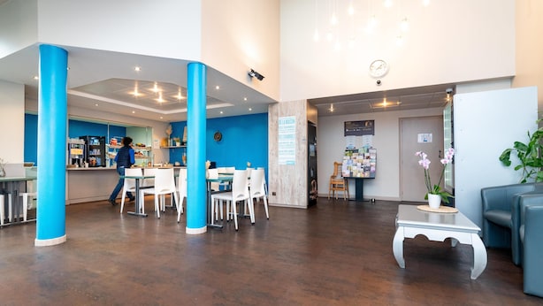 Un hall d’entrée spacieux avec un comptoir d’accueil, un espace salon et une horloge au mur.