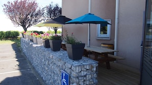 Un espace patio aménagé avec des meubles d’extérieur, des plantes en pot et des parasols.