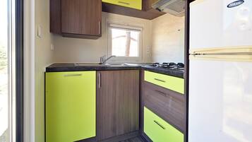 Una cocina compacta con armarios de madera y un refrigerador blanco.