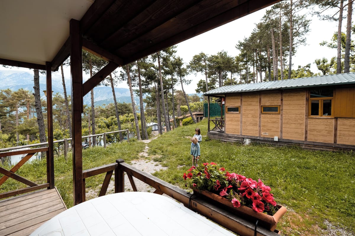 Uma cabana de madeira com vista para uma floresta e montanhas.
