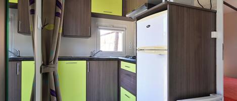 A compact kitchen with a window, a built-in microwave, and a refrigerator.