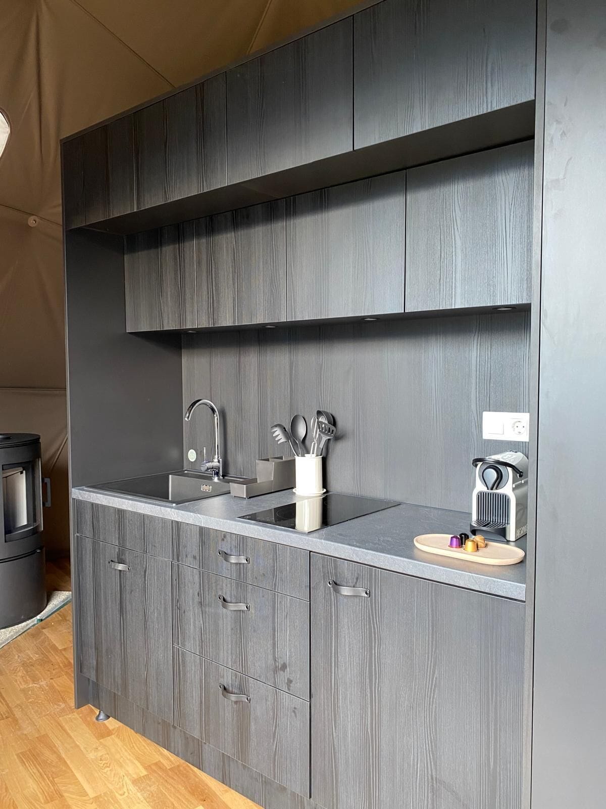 Une cuisine moderne avec des meubles de couleur grise, un évier en acier inoxydable et une machine à café.