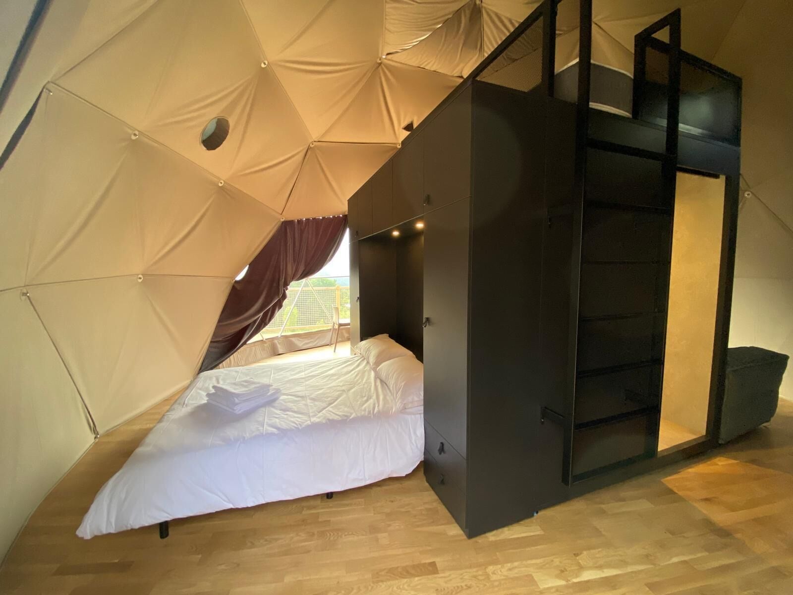 A tent-style room with a bed, a wardrobe, and a staircase.