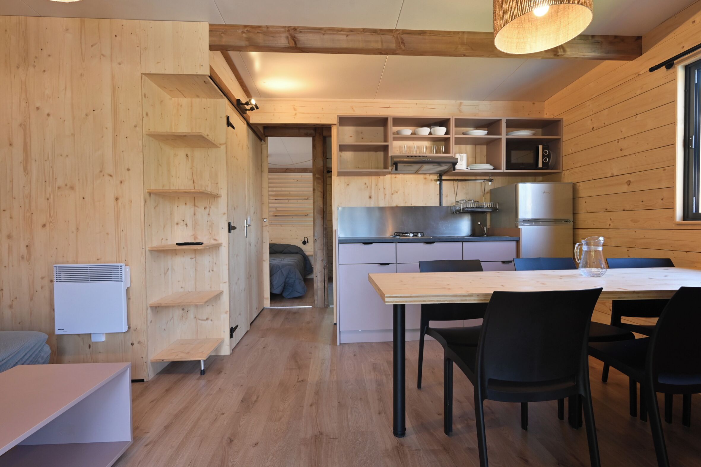 Una cocina compacta con paredes de madera, una mesa de comedor con sillas y un refrigerador pequeño.
