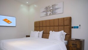 A bedroom with a large bed, a headboard, a bedside table, and a wall-mounted artwork. - Luxury House - Sleeps 8 & Free Parking (Abuja)
