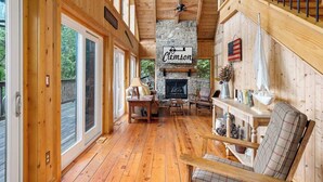 Een blokhutinterieur met een stenen openhaard, houten vloeren en een bordje met de tekst 'Clemson Vacation Rentals'.