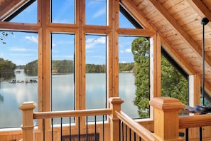 Une terrasse en bois offrant une vue sur un lac paisible et des bateaux amarrés.