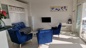Ett modernt vardagsrum med en soffa, fåtöljer, en tv och en balkong med utsikt.