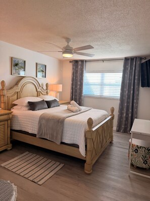 A neatly arranged bedroom with a bed, bedside tables, a ceiling fan, and a window with curtains.