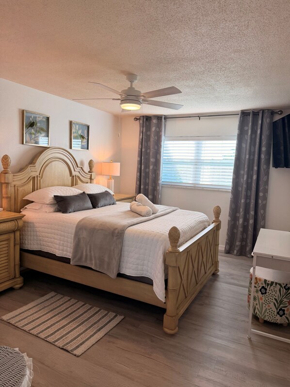 A neatly arranged bedroom with a bed, bedside tables, a ceiling fan, and a window with curtains. - Cozy 1 Bedroom by the Skyway Marina District (St. Petersburg)