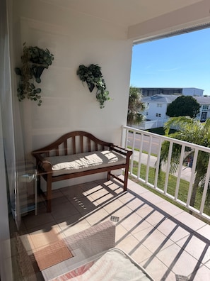 A balcony with a wooden bench, potted plants, and a view of a residential area. - Cozy 1 Bedroom by the Skyway Marina District (St. Petersburg)