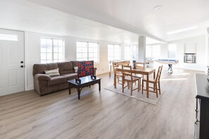 Relax in this inviting living area with a sofa, coffee table, and dining table, surrounded by large windows and a fireplace.