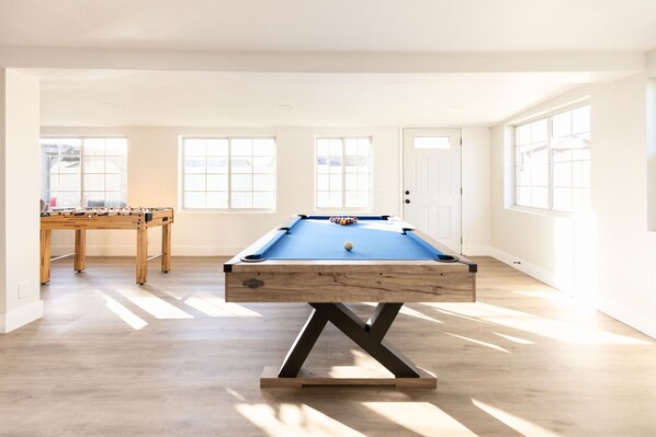 Enjoy a game of pool or foosball in this spacious room with a high ceiling and large windows.