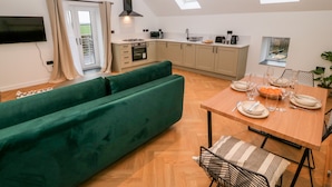 Una cocina moderna con comedor, un sofá verde y un televisor montado en la pared.