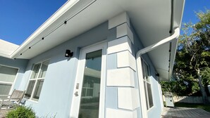 A corner of a building with a white exterior, a door, and a window.