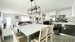 A modern kitchen with a central island, stainless steel appliances, and a dining area with a white table and chairs.
