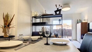 Une cuisine moderne avec un coin repas, comprenant un meuble intégré, une table à manger dressée avec des assiettes, des verres et des couverts, et une vue sur la ville par une grande fenêtre.